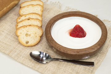 Yogurt in the wood cup have strawberry and bread breakfast food.
