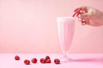 A hand grab a reusable eco-friendly metal straw that is in a raspberry milkshake