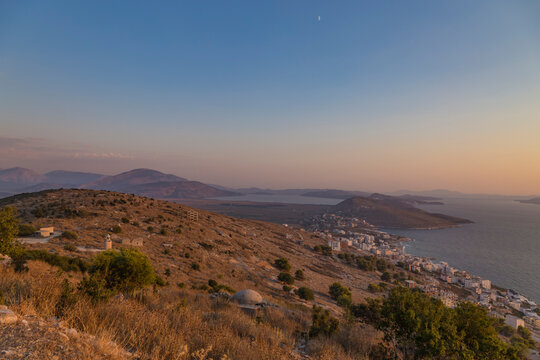 Beautiful sunset view from Lekuresi Castle (Saranda, Albania) to Ionian sea, old concrete bunker, small functioning lighthouse and island Corfu, Greece in the background