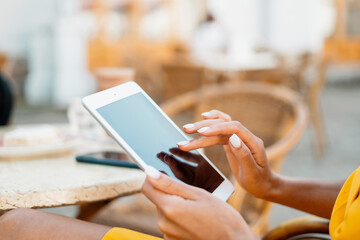 Manager online work remotely. Freelance Afro ethnika appearance works on a tablet in a summer cafe....