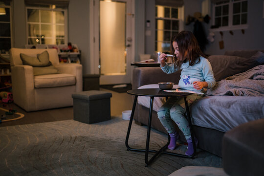 Girl Sitting On Couch Eating Cereal Early Morning