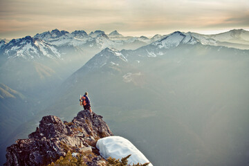 Hiker standing on the edge of a cliff looking out at scenic mountians