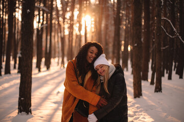 Portrait of happy lesbian couple embracing standing in park in winter