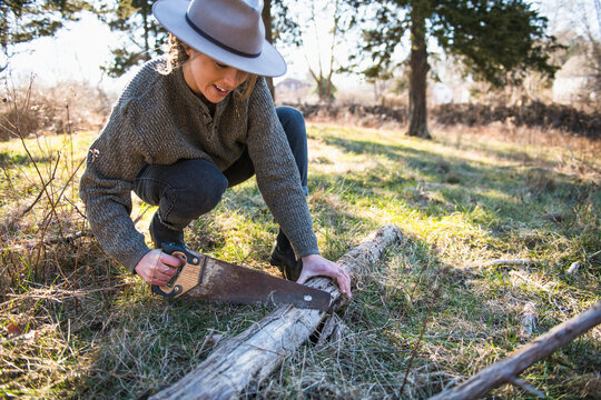 Woman Working with hand tools in farm field sawing fallen trees