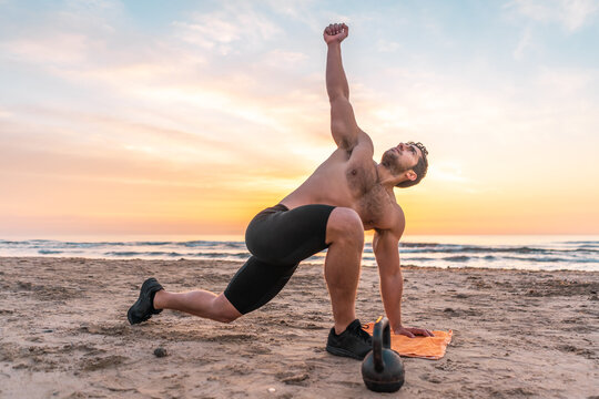 muscular man training on the beach at sunrise
