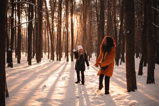 Happy female friends playing with snow in park during winter