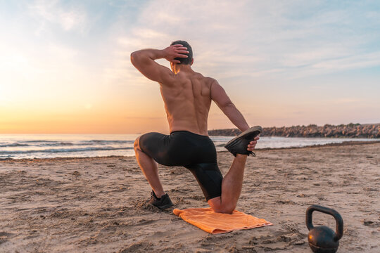 muscular man training on the beach at sunrise
