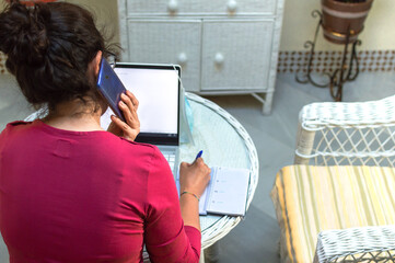 Back view of woman working at home and talking on the cell phone.