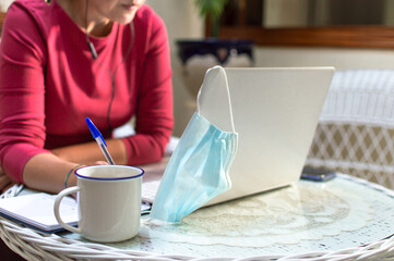 Unrecognized woman removes face mask to work from home. Working from home concept.