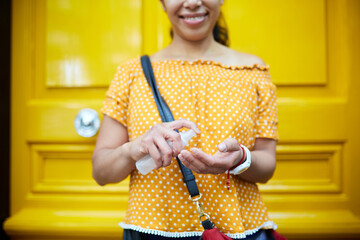 unrecognizable woman on the street applying hand sanitizer