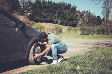 young man in wilderness accident checking car tire