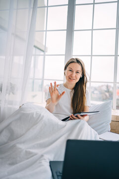 girl writes in a notebook and listens to music in bed