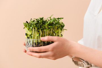 Woman with fresh micro green on beige background, closeup