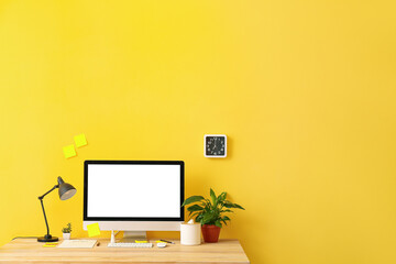 Modern workplace with computer and decor near color wall