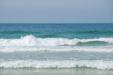 beach in summer day, blue sea, strong waves in the sea, sunny day, beach sand, clear sky