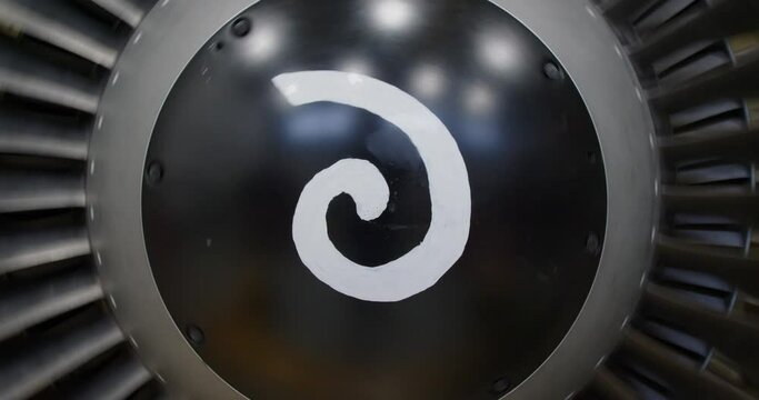 Concept of aircraft maintenance.  Close-up footage of a CFM56 jet turbine engine of aircraft spinning. Close view of the spiral on the spinner cone rotating.