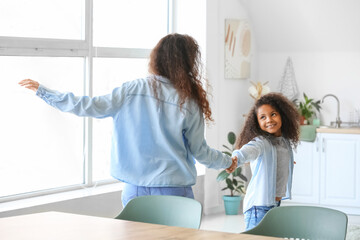 African-American little girl dancing with her mother at home