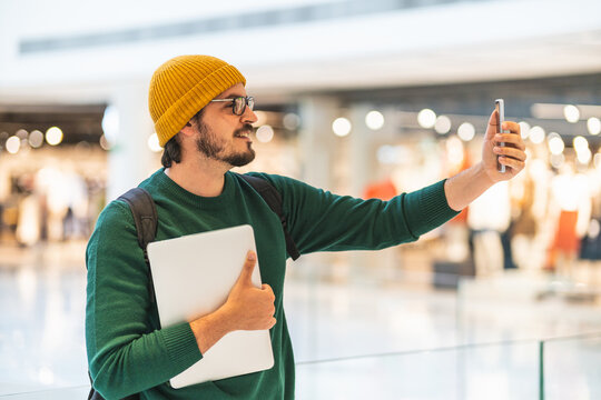 Spanish man talking on video call with smartphone in shopping mall