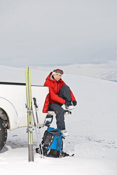 woman sitting on the back of pick up truck taking a break from skiing