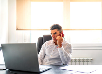 executive taking a call while working from his computer at home