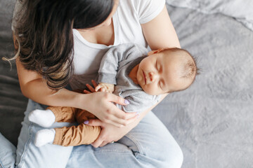 Mother holding rocking sleeping newborn infant baby son. View from top