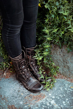 Womans legs in Black Jeans and Black Leather boots with green ivy