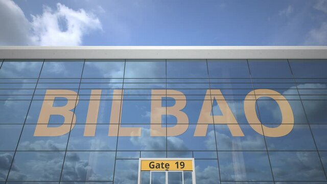 Airliner reflecting in the windows of airport terminal with BILBAO text