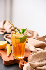 Glass of tasty ice tea with lemon on table in kitchen