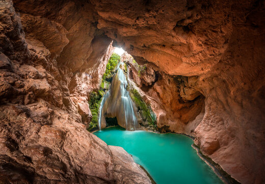 waterfall inside a cave and a lake of crystal clear turquoise water.