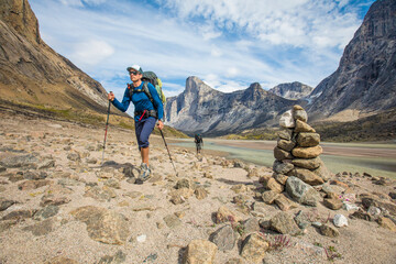 Backpackers hike past cairn, marking the trail / route.