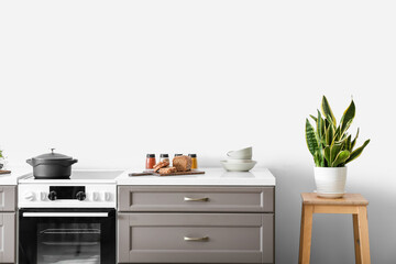 Obraz na płótnie Canvas Modern kitchen counter with electric stove near light wall