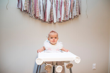 First birthday, baby girl sitting under birthday banner