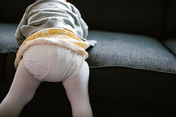 Detail of one year old girl climbing onto couch