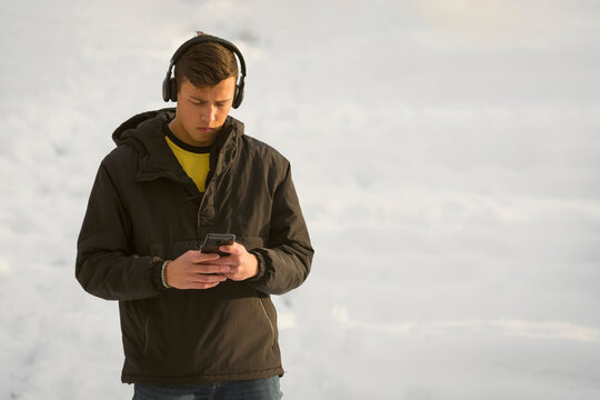 Blue-eyed millennial student boy listening music on headphones