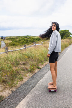 Young Woman skateboarding barefoot on overcast day