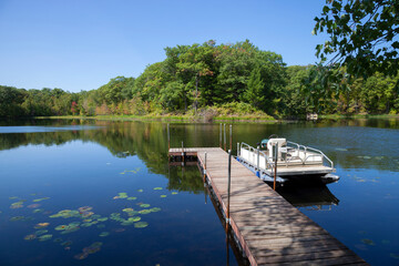 Fototapeta na wymiar Small lake in northern Minnesota with a dock and pontoon boat