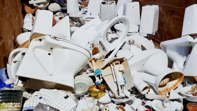 Ceramic trash in a recycling container. Broken toilet seats, kitchen ceramic ware, broken cups and plates.