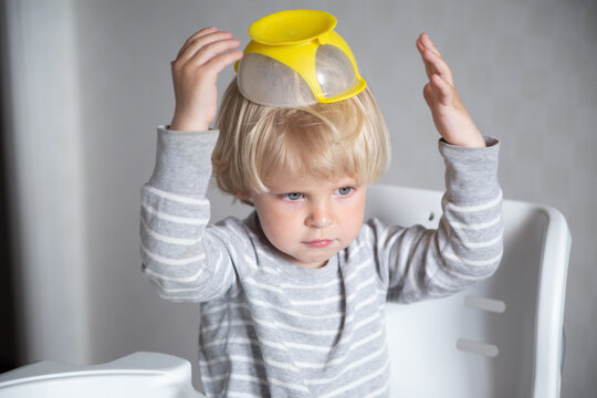 Caucasian boy does not want to eat, child put a plate on his head, lifestyle