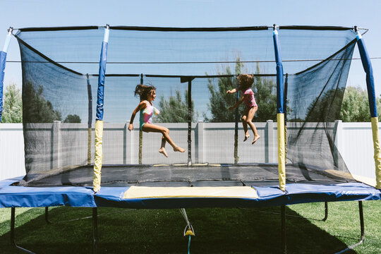 Sisters enjoying summer on the trampoline with a sprinkler