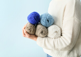 Woman holding knitting yarn on color background