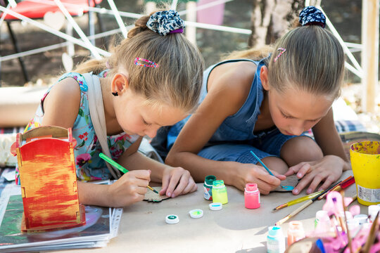 Girls paint with paints on wooden blanks. Street art festival