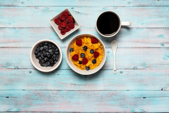 Bowl of cereal with blueberries and raspberries and coffee breakfast