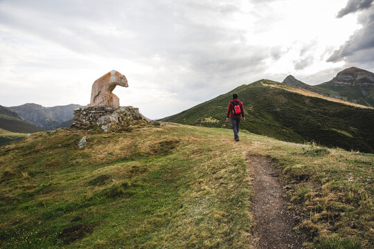Man walking in the mountain next to bear statue Picos de Europa