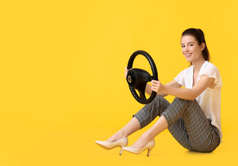 Young woman with steering wheel on color background