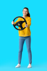 Young woman with steering wheel on blue background