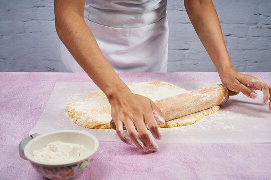 Flattening the dough with the rolling pin to prepare the alfajores.