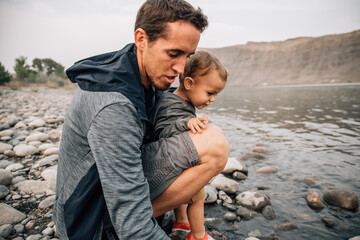 Dad and toddler son explore waters edge of Yellowstone River