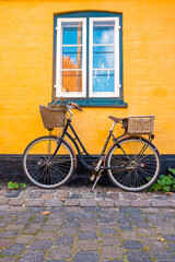 Fototapeta na wymiar Bicycle parked near yellow wall of an old house in a classical traditional European village.