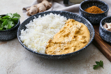 Bowl of tasty chicken curry with rice on light background