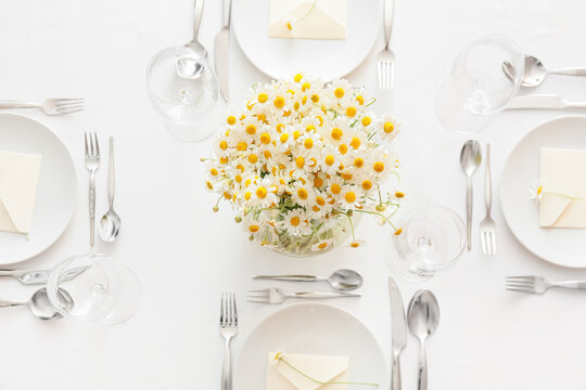 Stylish table setting and chamomile flowers on light background